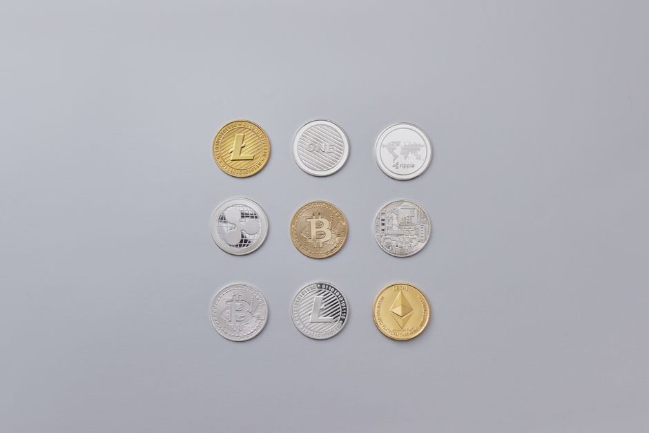 Assorted cryptocurrency coins on a neutral background, representing native altcoin staking that locks tokens