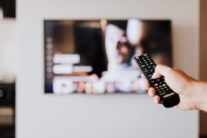 Hand holding a remote in front of a TV streaming a drama