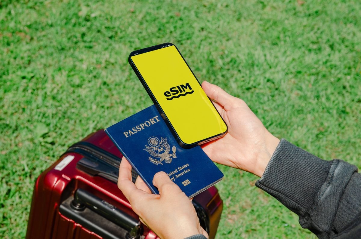 Traveler holding a smartphone with an eSIM travel data plan next to a passport, representing digital nomad connectivity in 2026