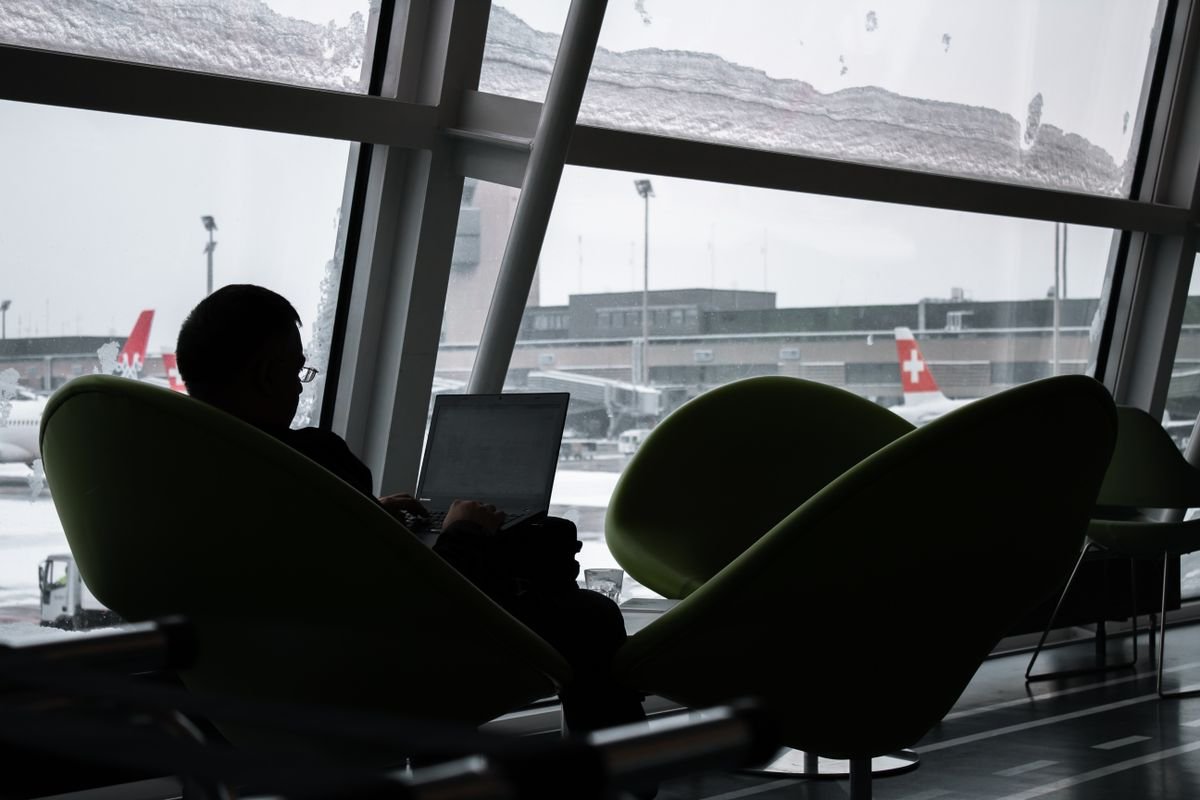 Digital nomad troubleshooting an eSIM not connecting abroad while working on a laptop in an airport lounge
