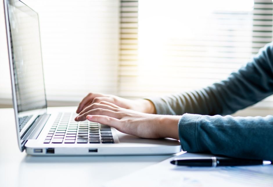 Close-up of hands typing a salary negotiation email on a laptop keyboard