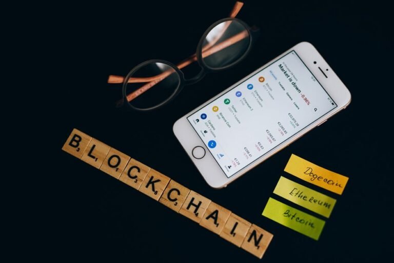 Smartphone displaying cryptocurrency market data beside a laptop, representing altcoin staking research in 2026