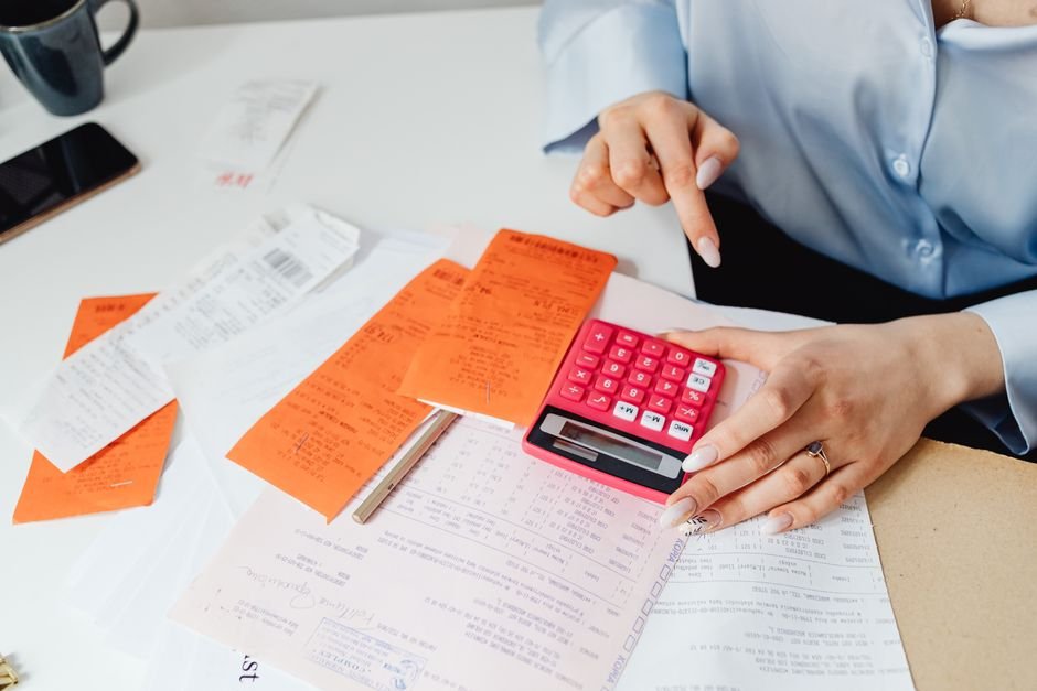 Person adding up paper receipts with a calculator to track side hustle business deductions
