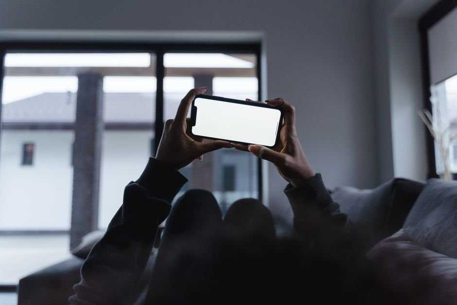 Person checking a streaming app on their phone while relaxing on a couch