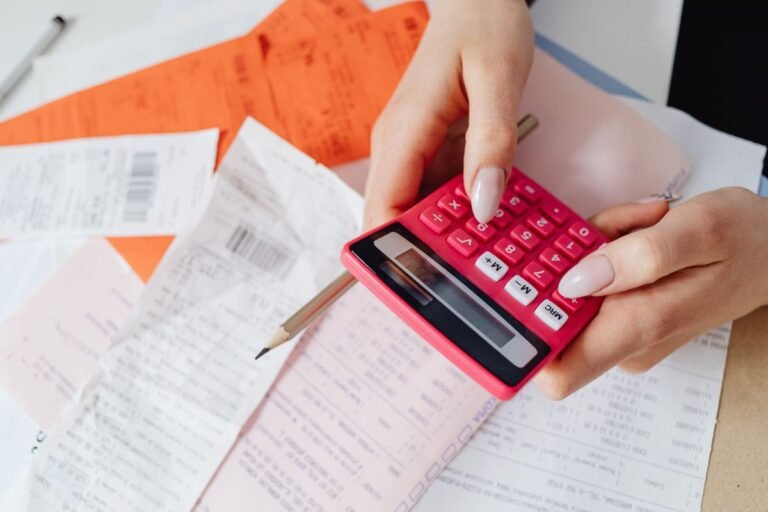 Close-up of a person using a calculator with receipts, representing tracking gig income for taxes