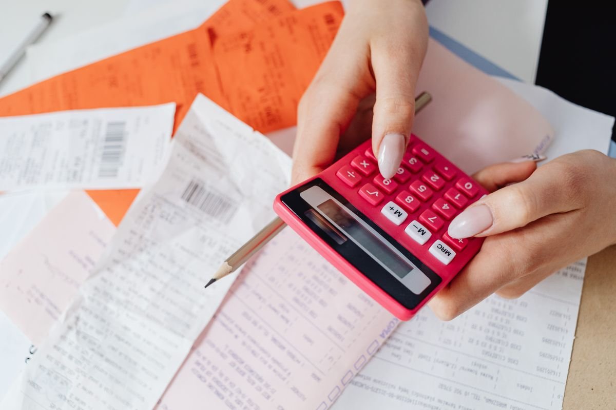 Close-up of a person using a calculator with receipts, representing tracking gig income for taxes