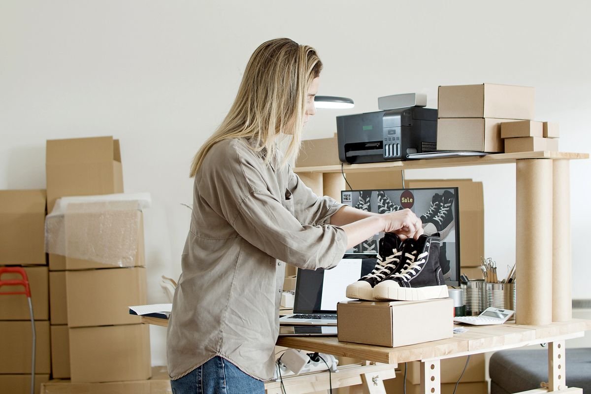 Person packing a shoe box for resale, representing an online seller preparing an order