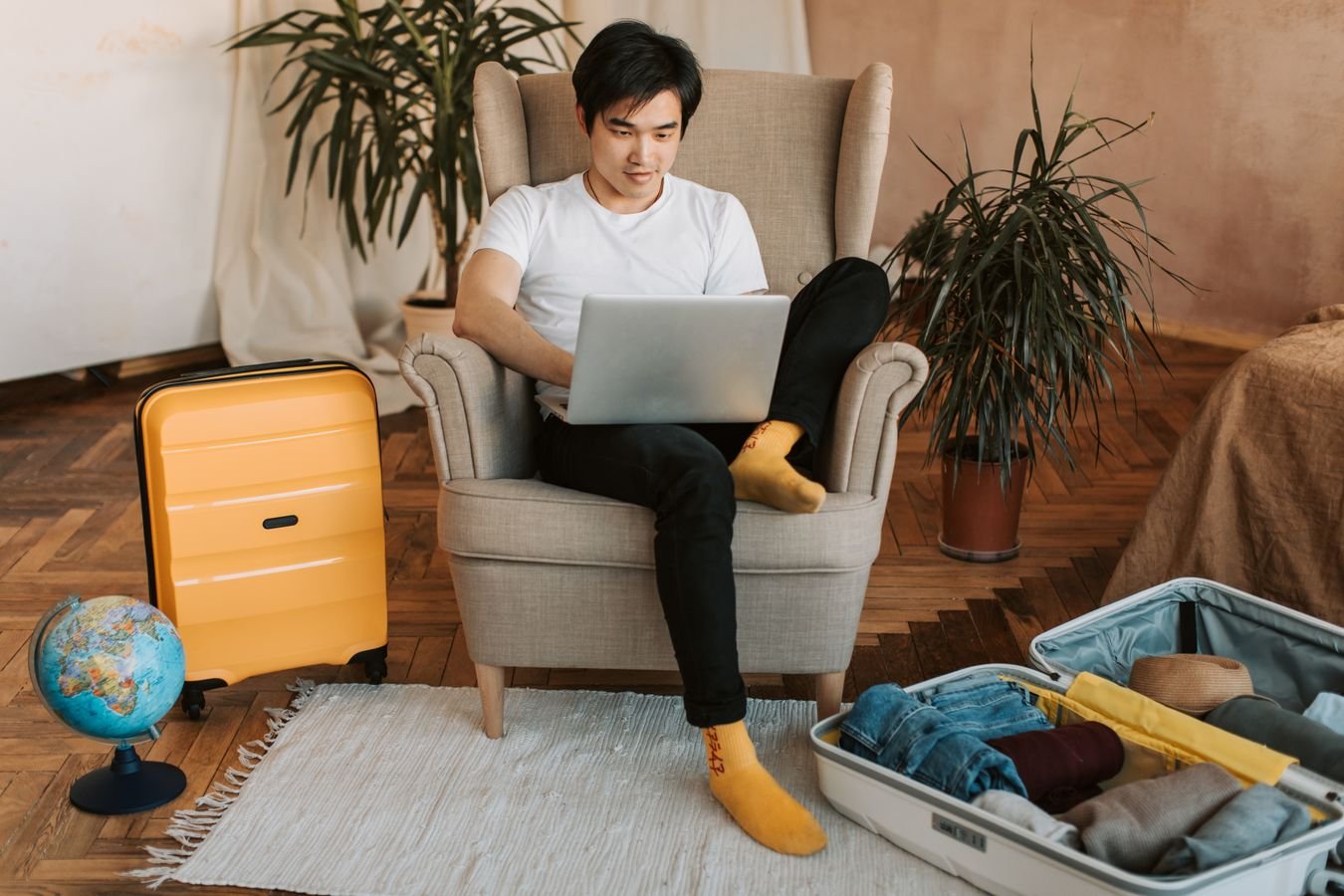 Traveler checking a booking confirmation on a laptop next to a packed suitcase