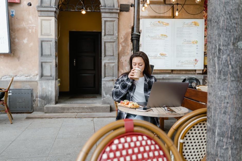 Remote worker with a laptop and coffee at an outdoor cafe in a European city