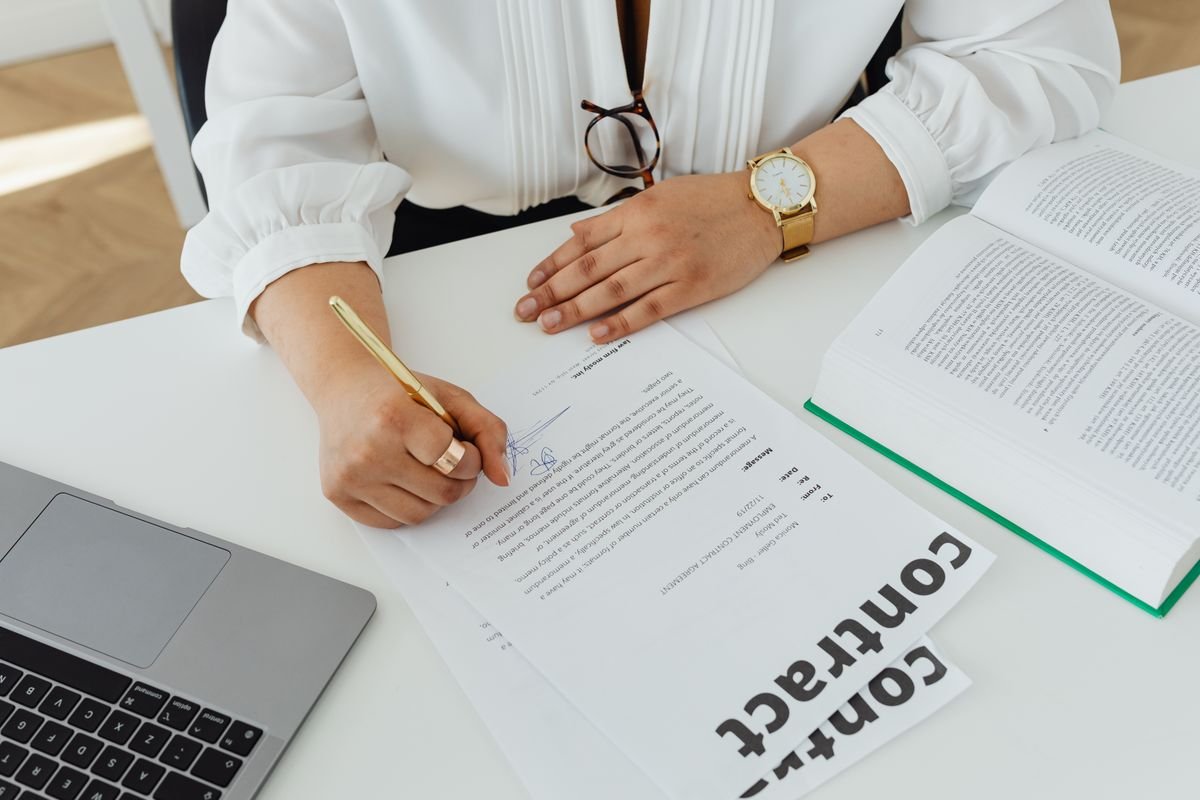 Close-up of a person reviewing and signing a membership cancellation document at a desk