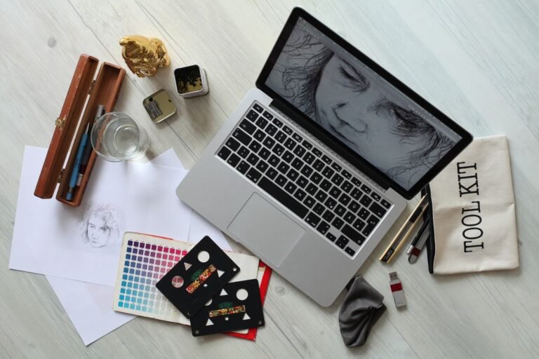Creative workspace with laptop and design supplies, representing Canva Pro used for a print-on-demand or Etsy side hustle