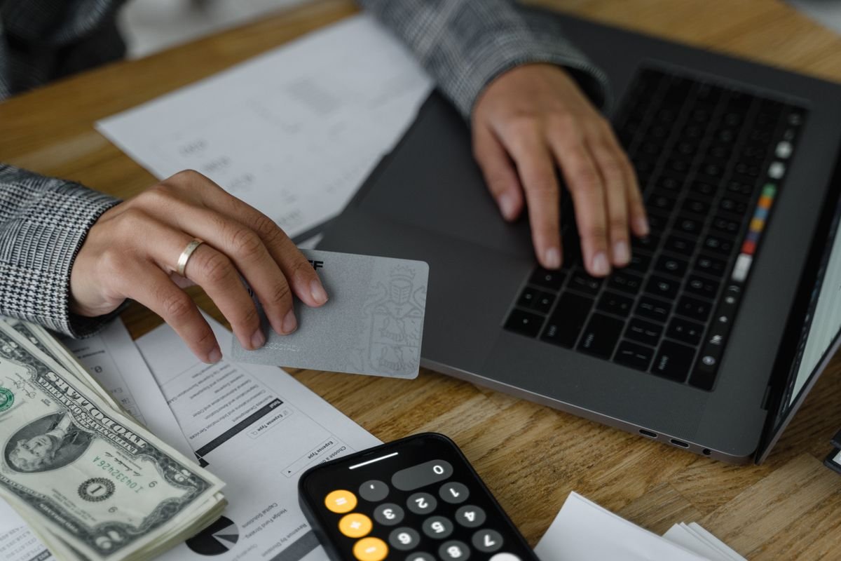 Person entering a credit card into a laptop, representing a Canva Pro billing and refund request