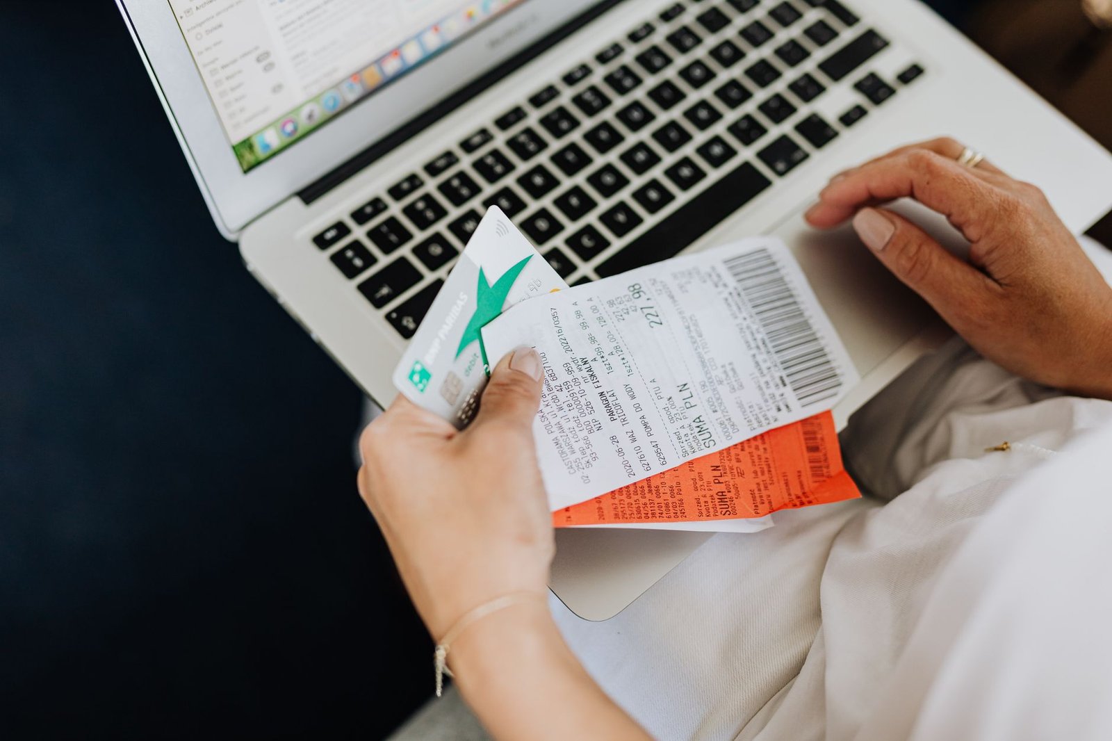 Shopper reviewing a receipt and bank card next to a laptop before deciding whether to request a refund