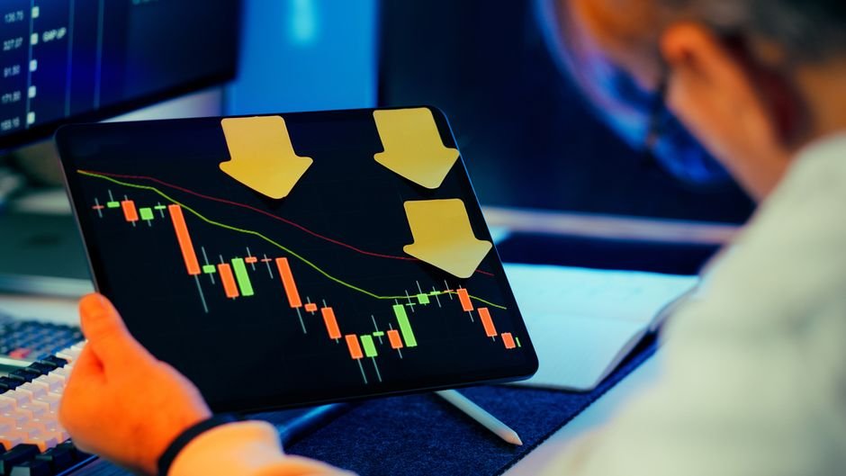 Trader reviewing a falling market chart on a tablet, representing a margin call and liquidation risk scenario