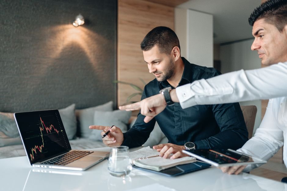 Two traders reviewing funding rate and futures data side by side on a laptop
