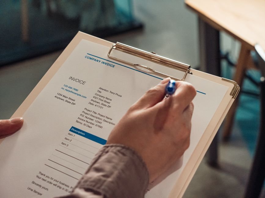 Freelancer reviewing an invoice and billing paperwork on a clipboard