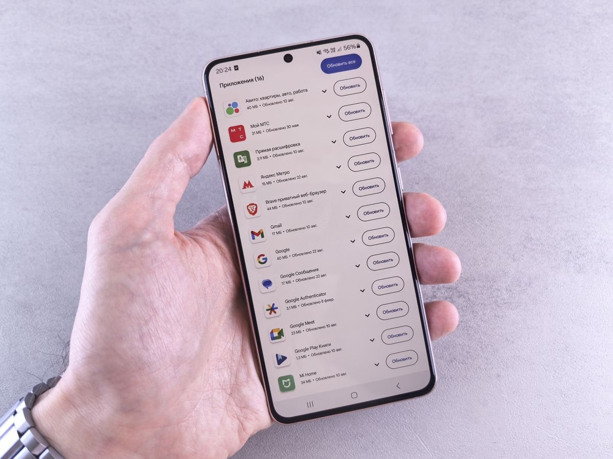 Hand holding an iPhone showing an app update screen, representing installing the iOS 27 public beta