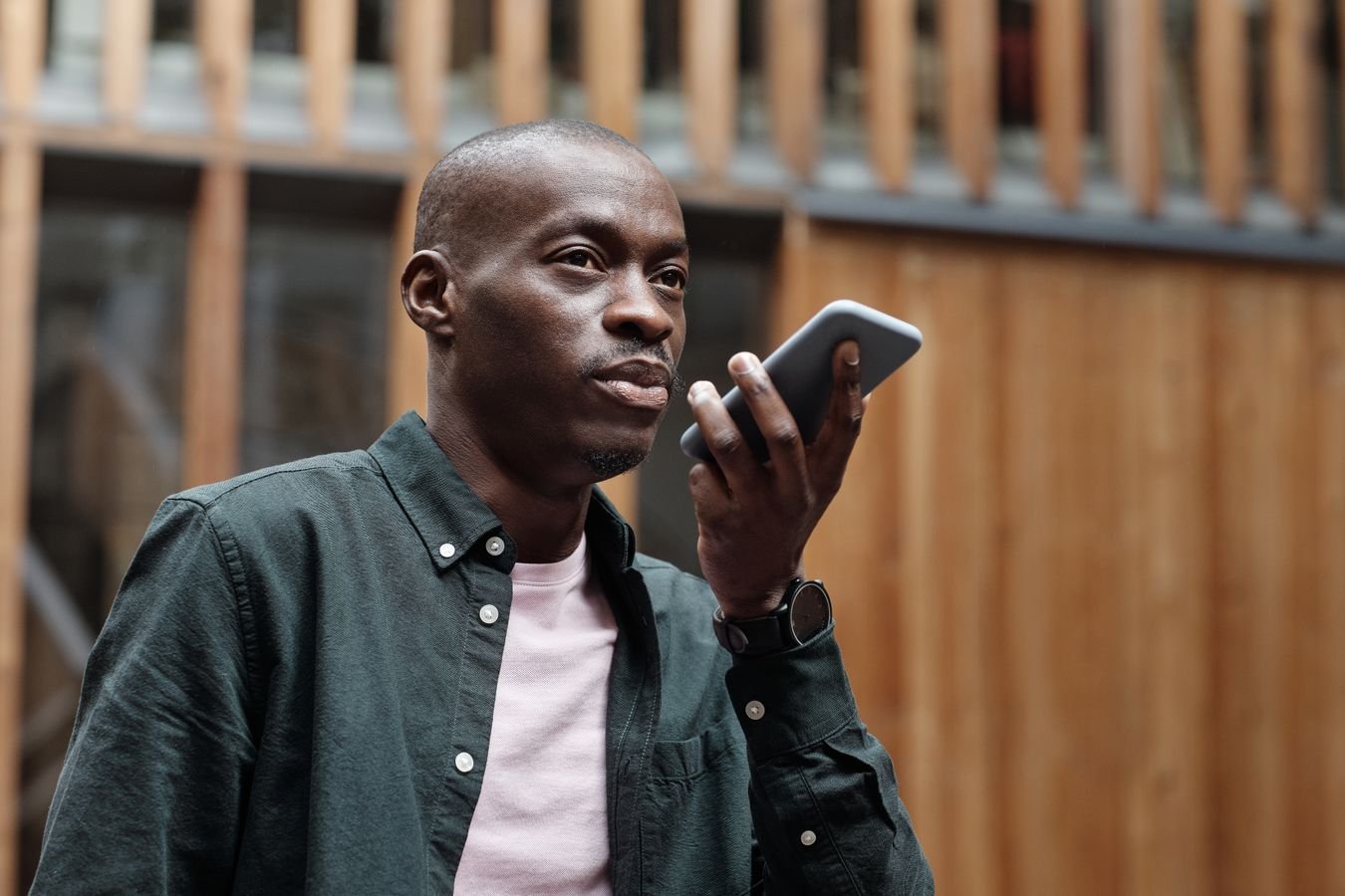 Person outdoors using voice commands on a smartphone, representing the rebuilt Siri experience in iOS 27
