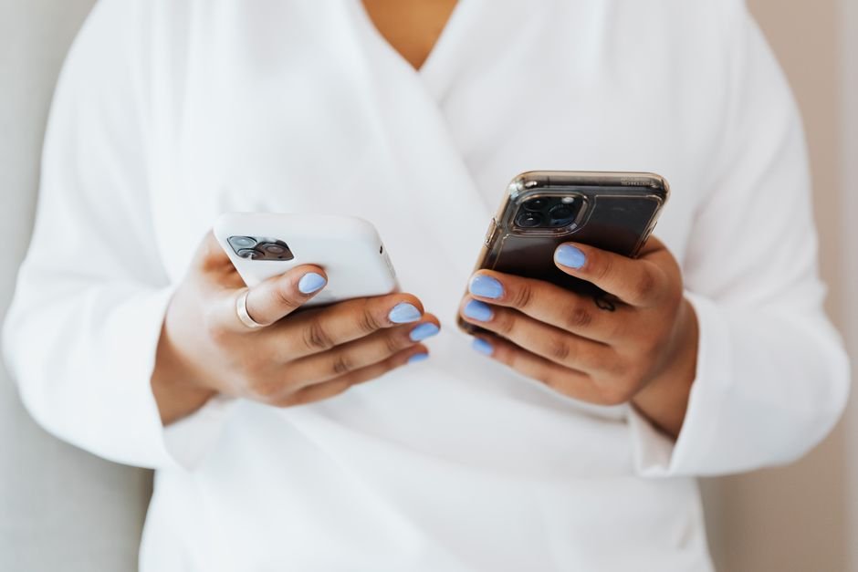 Person comparing two smartphones side by side, representing the decision to upgrade now or wait for the iPhone 18 Pro