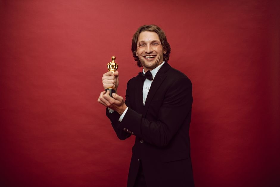 Person in formal attire holding an award trophy, representing music award nominations