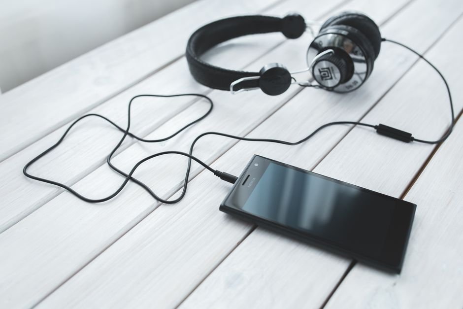Smartphone and headphones for streaming music, representing listening to a new album on release day