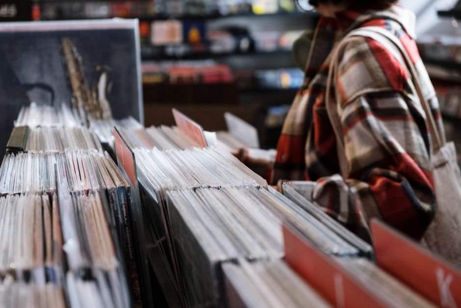 Shopper browsing shelves of vinyl records in a record store
