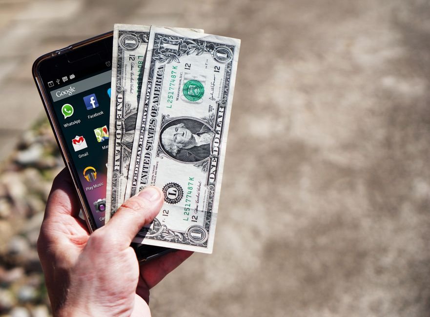 Smartphone with US dollar bills representing mobile banking while traveling abroad