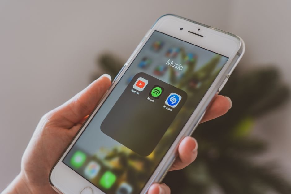 Close-up of a smartphone screen showing music streaming and chart apps