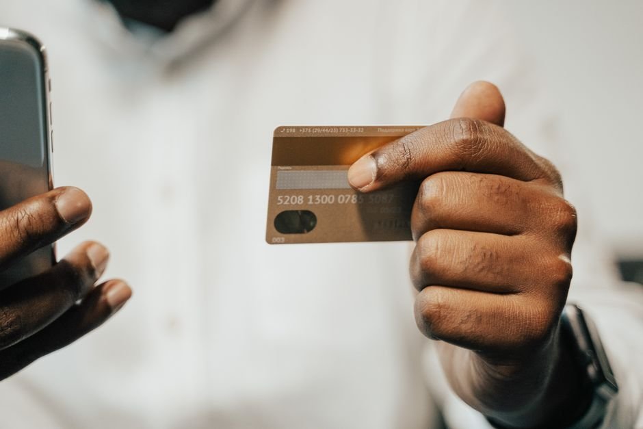 Person holding a credit card next to a phone to check a refund payment status