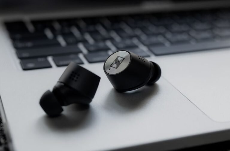Wireless earbuds resting on a laptop keyboard, representing a Bluetooth device that disconnected after a Windows 11 24H2 update