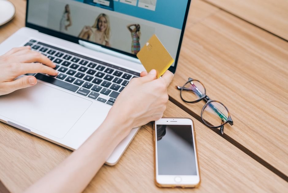 Person checking a shopping deal on a phone while holding a credit card