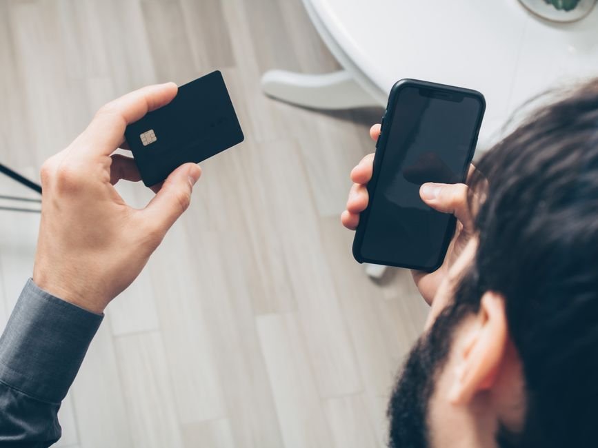 Person checking a payment card and phone while reviewing an online refund