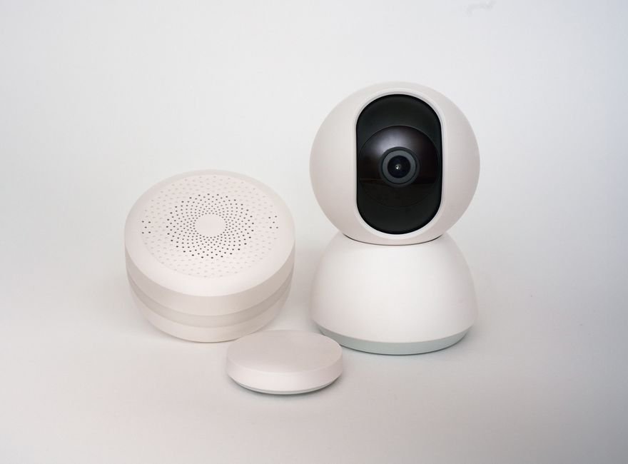 Minimalist smart home devices including a security camera and sensors, representing Matter-compatible hardware