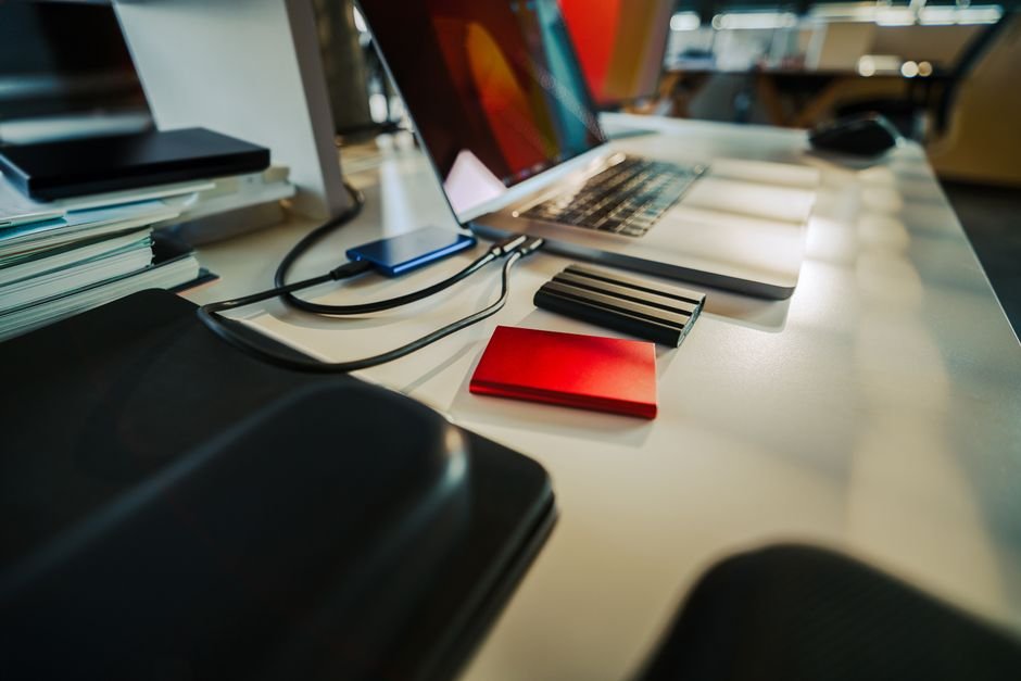 Desk with a laptop and several external hard drives used for backups