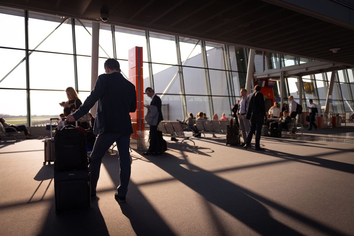 Travelers with carry-on luggage in an airport departure terminal before check-in
