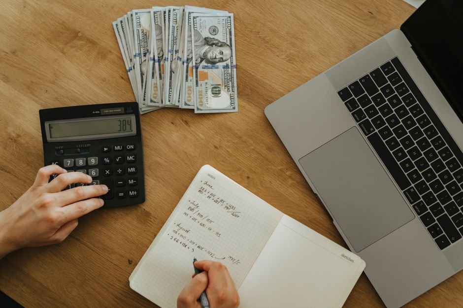 Hands using a calculator and notebook to plan trading costs