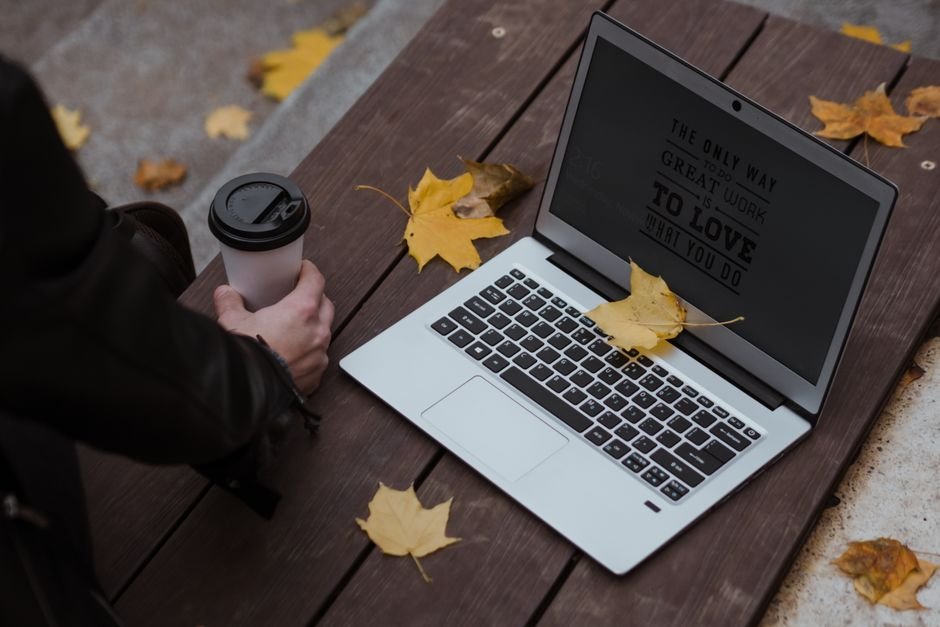 Laptop on a bench among yellow maple leaves, representing working remotely from Canada as a visitor