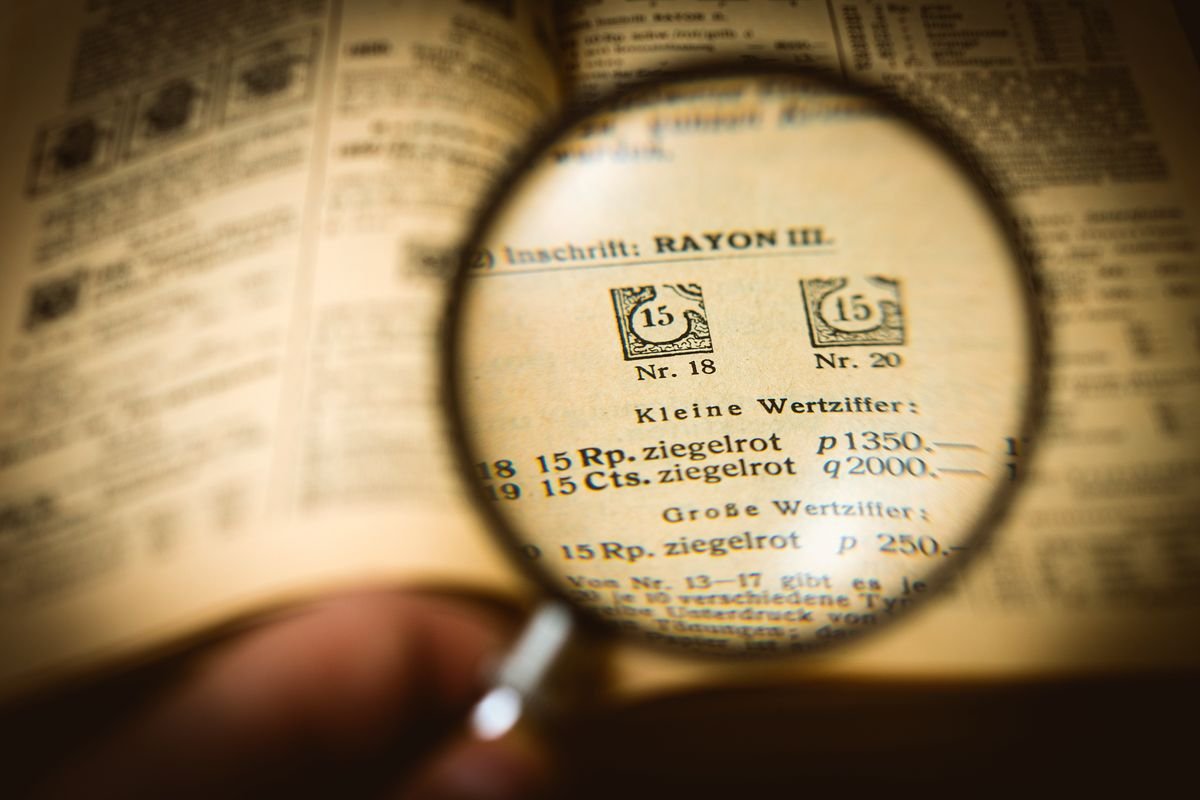 Magnifying glass over printed text, representing watermark detection on ChatGPT writing