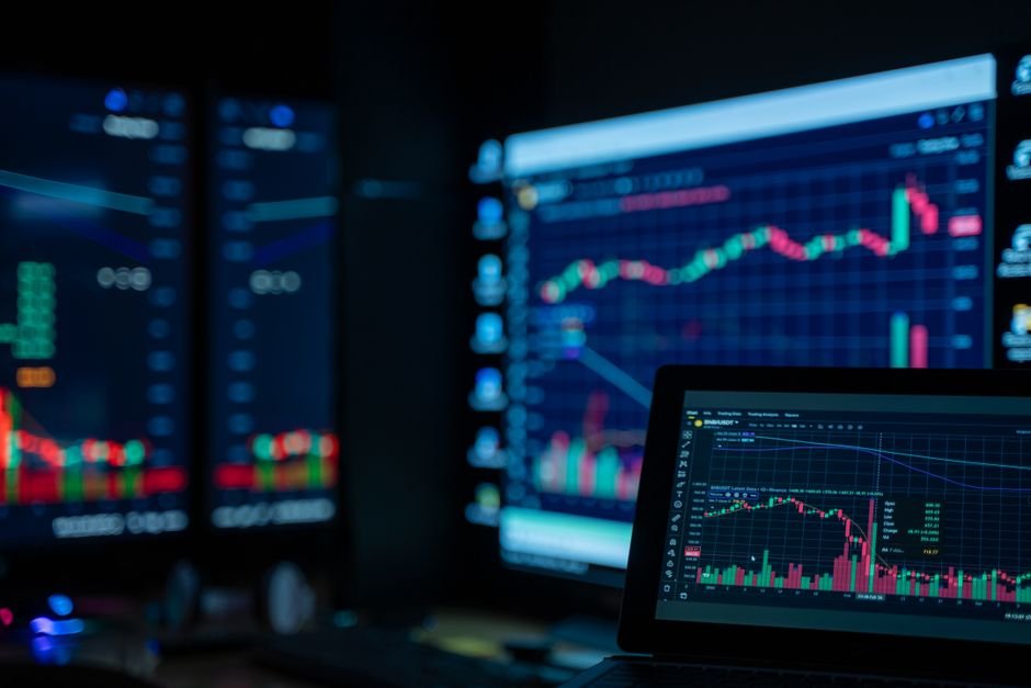 Monitors showing stock charts in a dim room