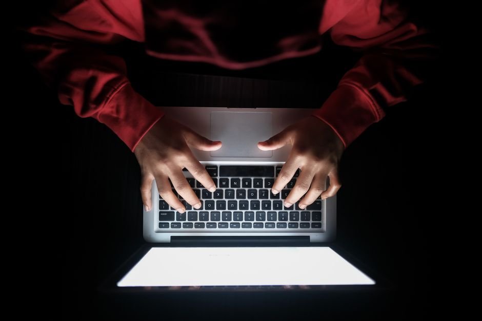 Hands typing on a laptop in a dark room, representing everyday Claude users checking the new usage rules
