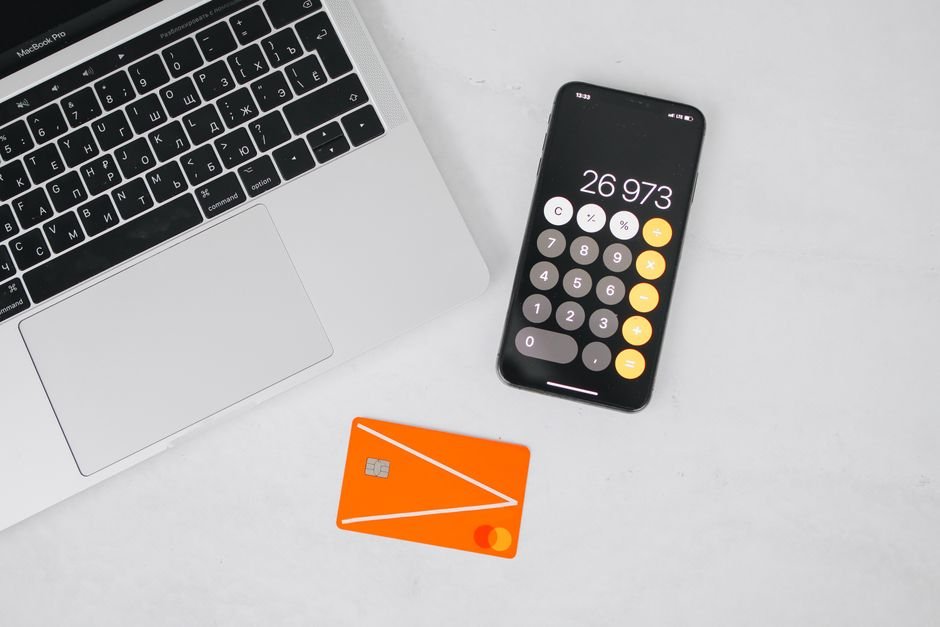 Phone calculator next to a laptop and credit card, for comparing Disney+ plan costs