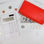 Wallet and coins beside a calculator for tracking a card balance