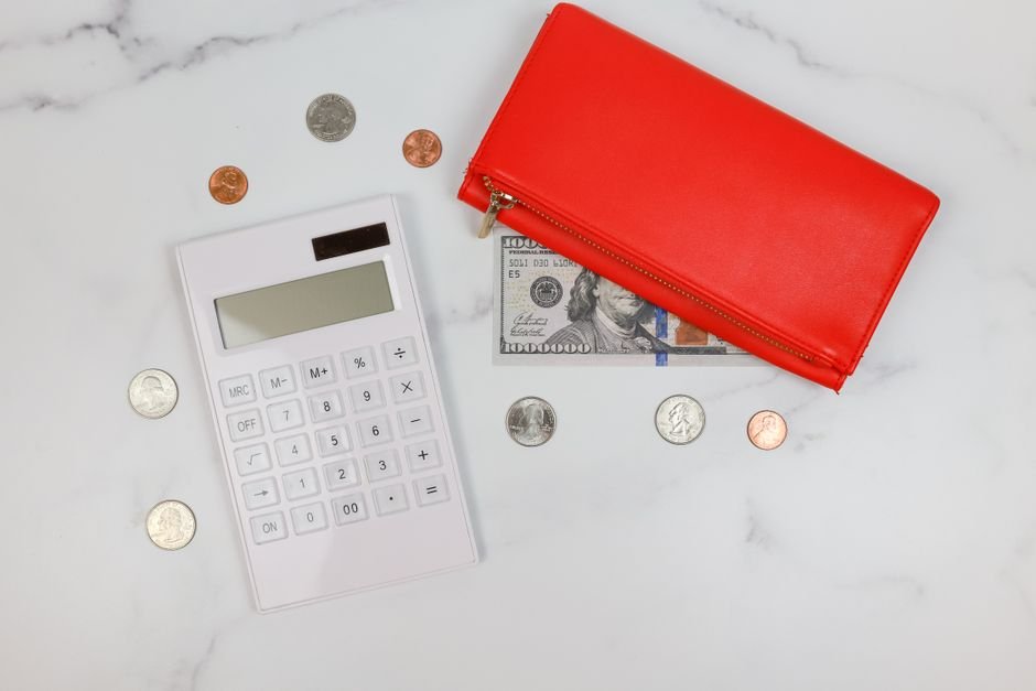 Wallet and coins beside a calculator for tracking a card balance