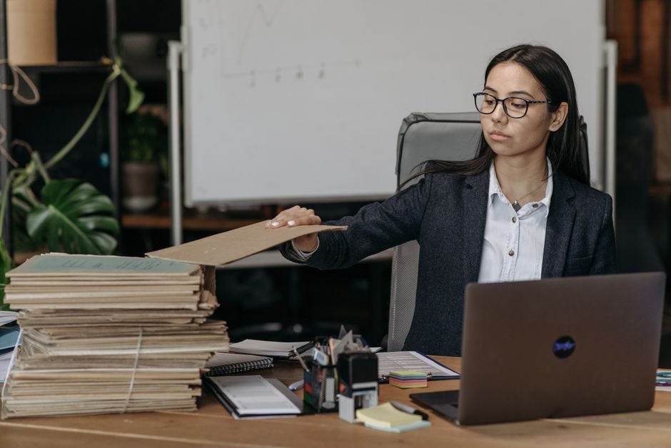 Person organizing a stack of files beside a laptop before migrating Gem knowledge files