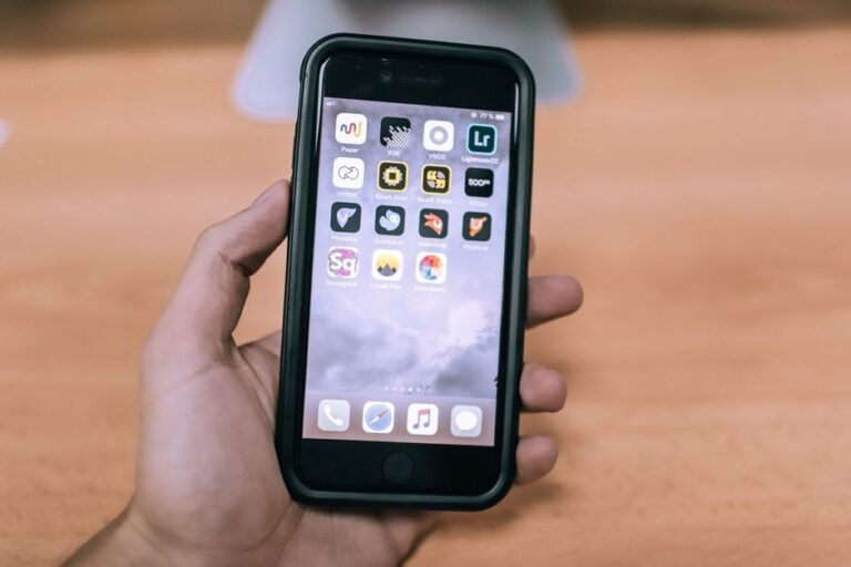 Hand holding an iPhone home screen, representing installing the iOS 27.0.1 bug-fix update