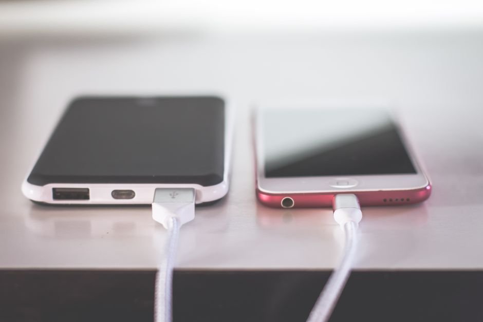 Two smartphones charging side by side, illustrating battery drain after the iOS 27 update