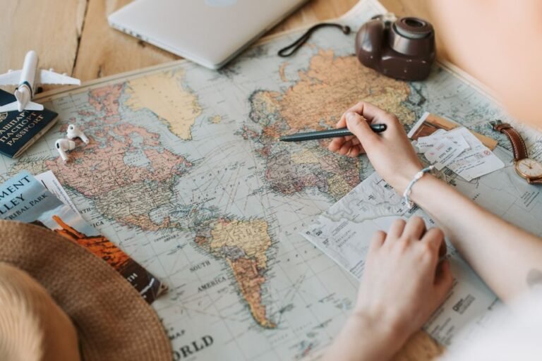 Hands marking destinations on a world map with passport and camera