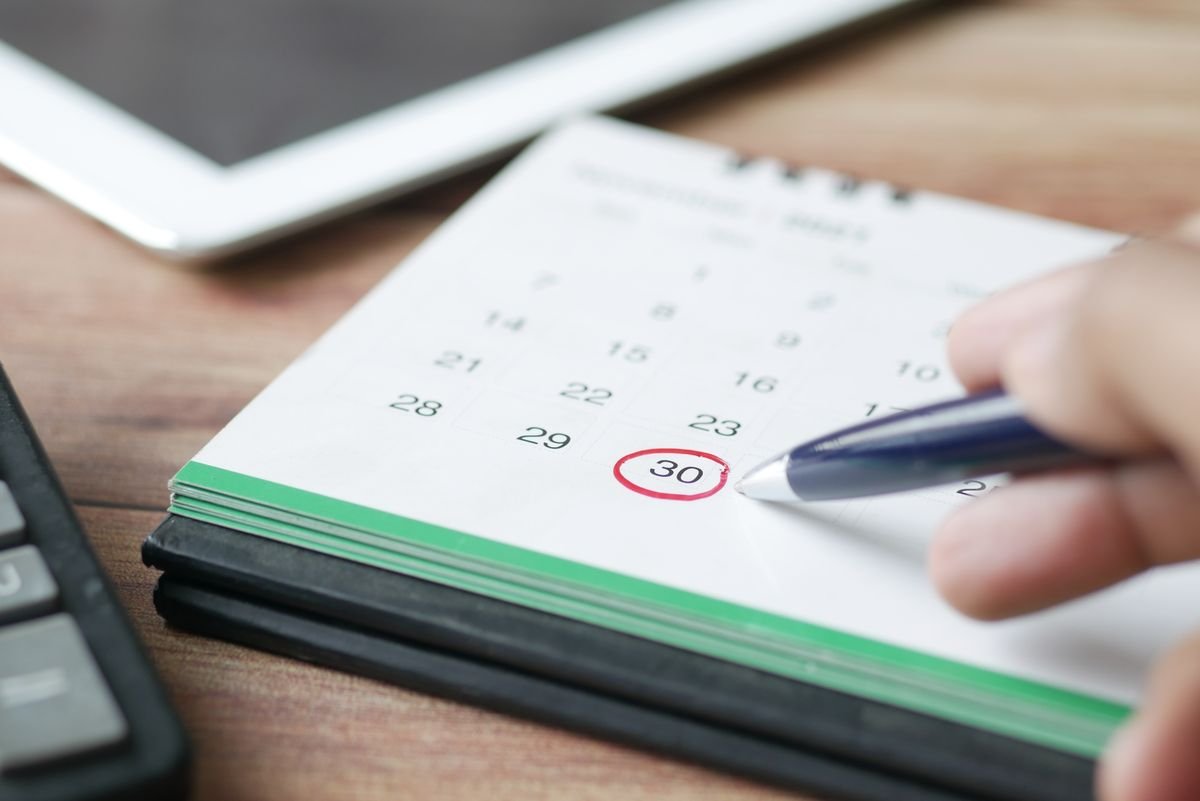 Hand marking a date on a calendar, illustrating the Kraken October 23 delisting deadline