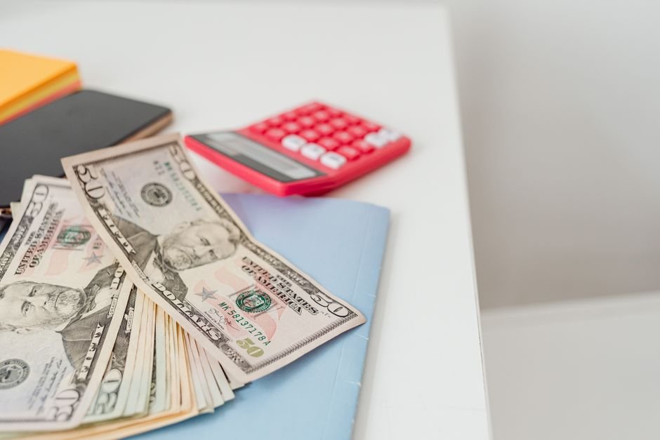 Notebook, US dollars and a calculator on a desk, illustrating the day-by-day math of a 3x leveraged ETF