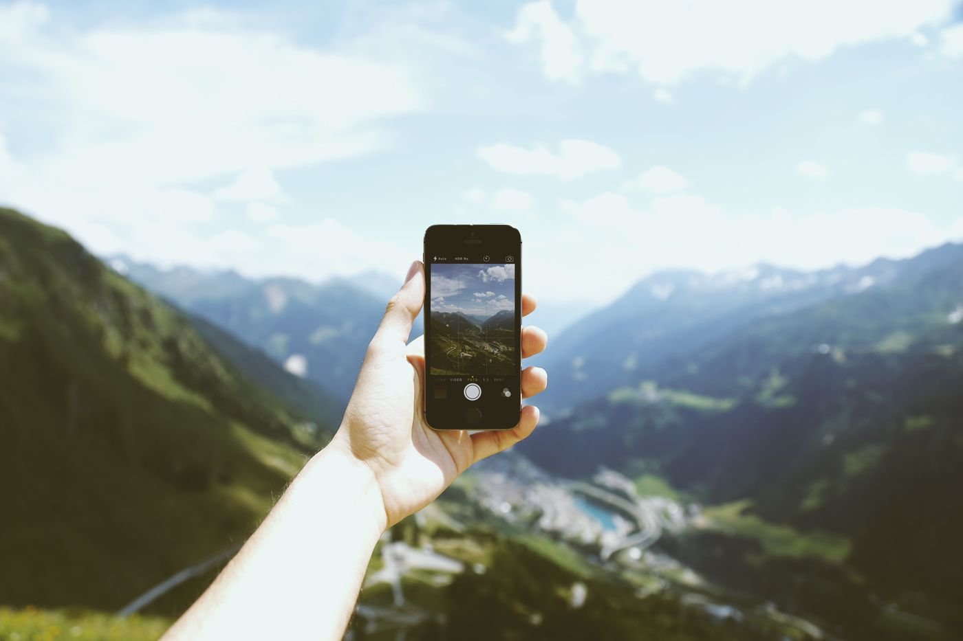Hand holding a phone taking a mountain photo, the kind of picture lost in a factory reset without backup